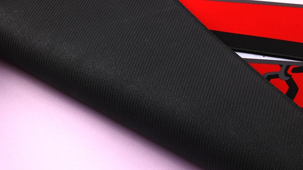Folded corner of a printed desk mat showing the textured black reverse surface