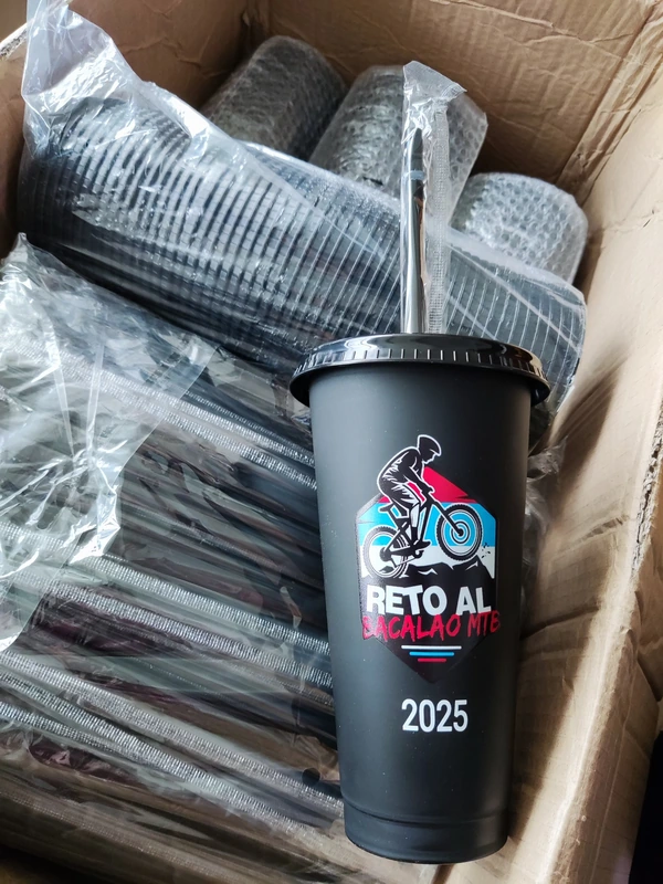 Black branded tumbler with straw shown beside individually wrapped items in a shipping carton