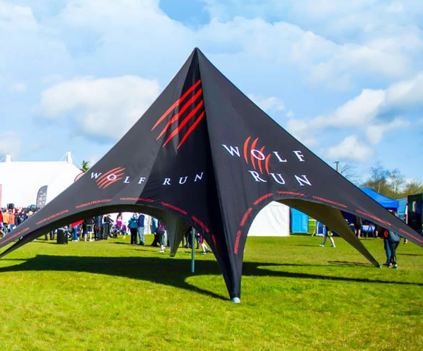 Black Wolf Run star-shaped tent with red graphics on grass beneath a blue sky