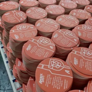 Large stacks of red round paper coasters with white Aperol Spritz artwork and lettering