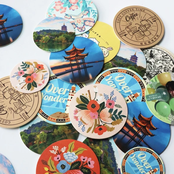 Assorted round coasters with floral, landscape, coffee and colorful printed artwork