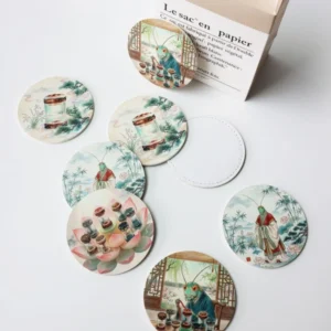 Round printed coasters featuring detailed illustrated scenes arranged beside a gift box