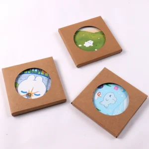 Three printed round coasters displayed in individual kraft boxes with circular windows