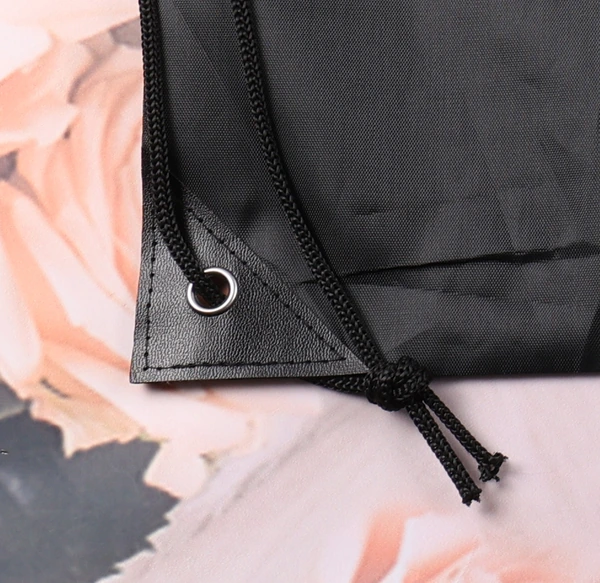 Close-up of a black drawstring bag corner with a metal eyelet and tied cord