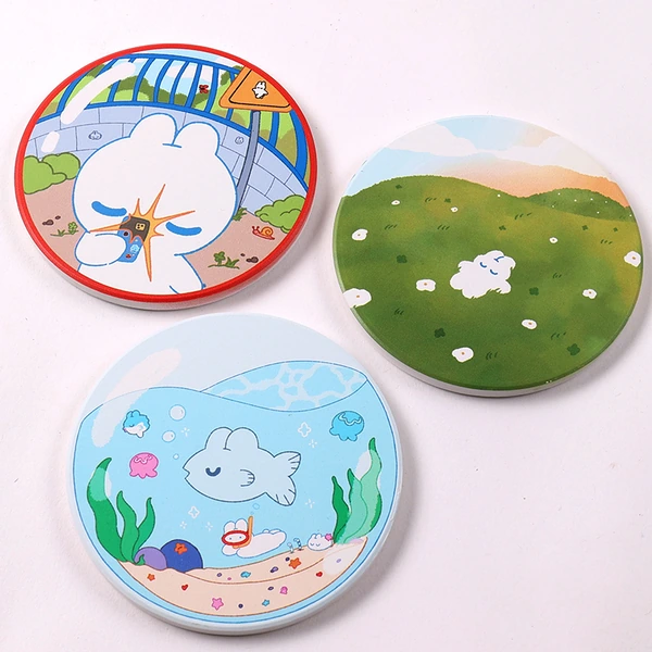 Three round coasters with colorful illustrated designs on a light background
