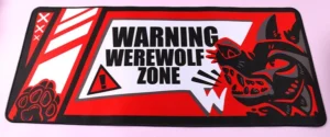 Rectangular red and black desk mat with a werewolf illustration and warning text
